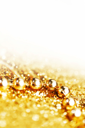 Golden decorative christmas beads on glitter background with white copy spaceの写真素材