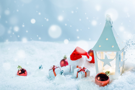 Christmas holidays card with gifts , balls , sants claus hat and glowing lantern in snowの写真素材
