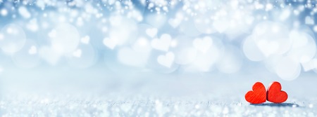 Two small handmade red wooden hearts on bright heart lights bokeh backgroundの写真素材
