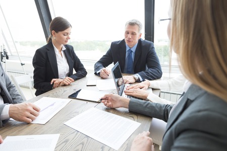 Mixed group of white collar workers at business meeting discuss documentsの写真素材