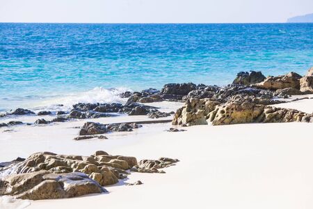 White fine sand coral beach with stones and blue tropical sea in Thailand