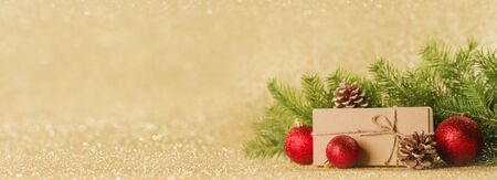 Christmas toys, decorations, present gift box wrapped in kraft paper on golden glitter background,...