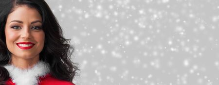 Beautiful happy woman in Santa Claus clothes on glowing lights bokeh backgroundの写真素材