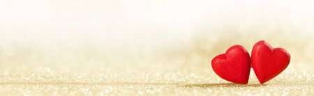 Two handmade wooden red hearts on golden glitter bokeh background. Vintage style. Love Valentine's Day concept.の写真素材