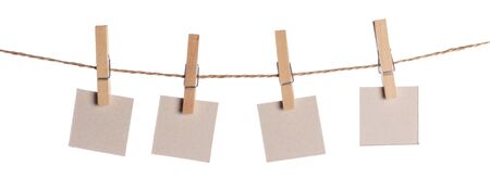 Set of four blank paper notes held on a string with clothespins isolated on white backgroundの写真素材