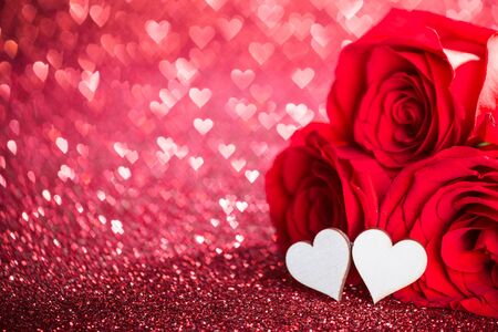 Three red roses and decorative hearts over bokeh glittering backgroundの写真素材