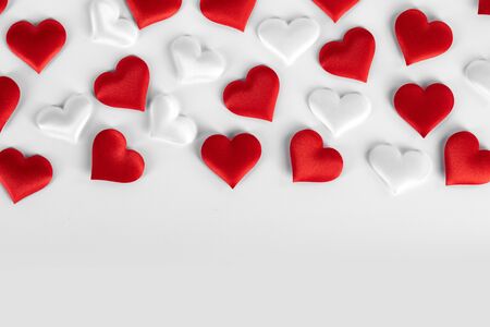 Valentine's day many red and white silk hearts on white background , border frame with copy space, love conceptの写真素材