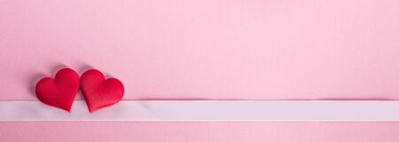 Valentine's day two red silk hearts and ribbon stripe on pink background, love concept