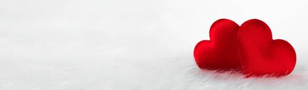Two red silk hearts on white fur background with copy space for textの写真素材