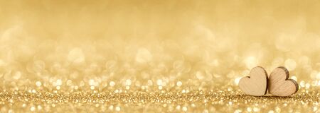 Two small handmade wooden hearts on bright golden lights bokeh background Valentines day card