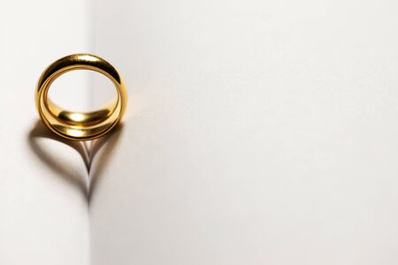 Two golden wedding rings on blank book pages background with copy space for text