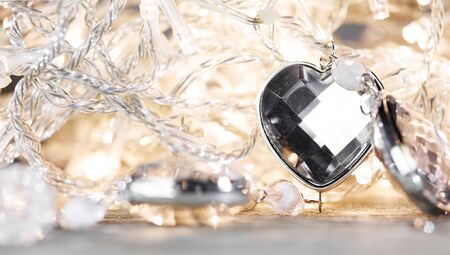 Heart shaped gem stones on golden lights of electric garland with bokehの写真素材
