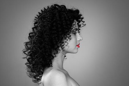 Profile portrait of young caucasian woman with curly hair and red lipsの写真素材