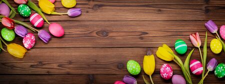 Hand-painted easter eggs with tulips on wooden background copy space for textの写真素材