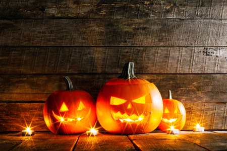 Halloween pumpkin head lanterns and burning candles on wooden backgroundの写真素材