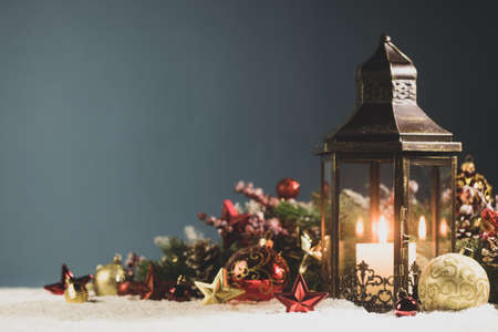 Glowing Christmas lantern and decor of fir tree branches and baubles in snowの写真素材