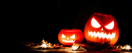 Halloween pumpkin head lanterns and burning candles on black backgroundの写真素材