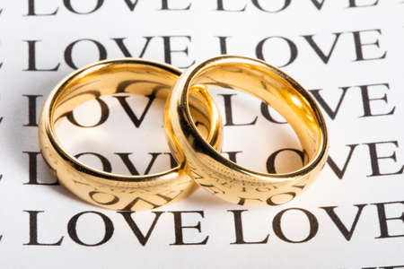 Two golden wedding rings with a word love close upの写真素材