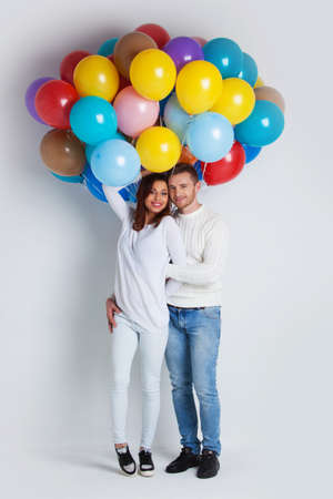 Young couple with many colorful balloons on white backgroundの写真素材