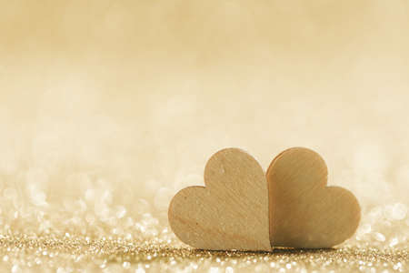 Two small handmade wooden hearts on bright golden lights bokeh background Valentines day cardの写真素材