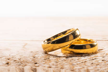 Two golden wedding rings on wooden background with copy space for textの写真素材