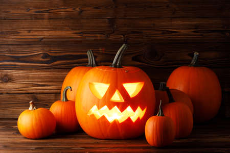 Glowing Halloween pumpkins on old wooden backgroundの写真素材