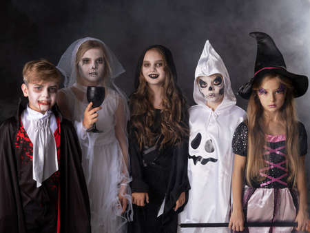 Happy Halloween party with children trick or treating in different costumes ghost, vampire, skeleton, witchの写真素材