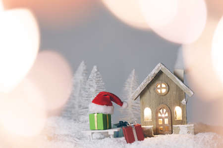 Magic Christmas card with toy wooden house in winter forest and gifts, bokeh lights aroundの写真素材
