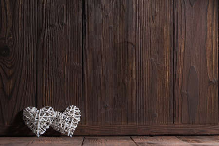 Two wicker hearts on brown wooden background with copy space for text, Valentine day designの写真素材