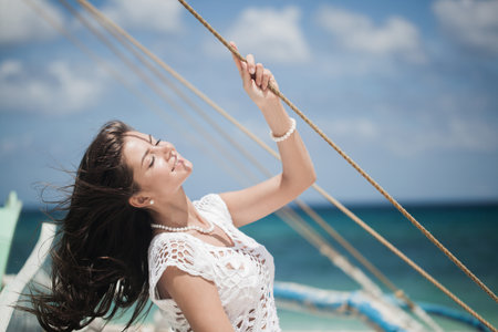 Summer travel on the yacht. Young happy woman on boat deck enjoy wind sailing the seaの写真素材