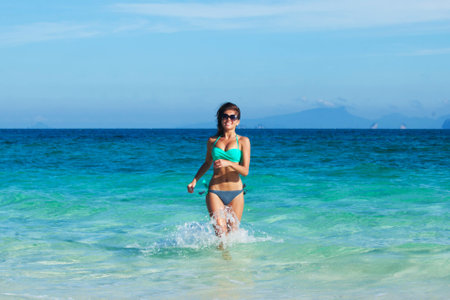 Beautiful fit woman in bikni run to tropical beachの写真素材