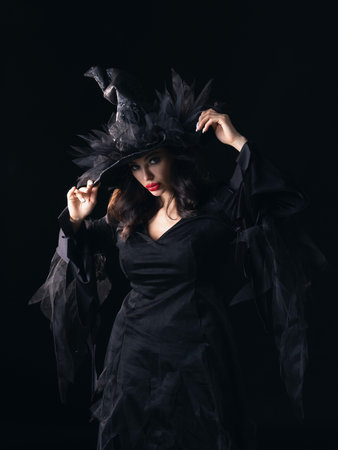 Halloween Witch. Portrait of a charming young witch in a hat and dress with elegant make-up....