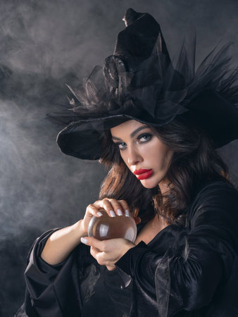 Woman in Halloween witch fortune teller costume with crystal ball. Beautiful sexy model girl in sinister costume and make upの写真素材