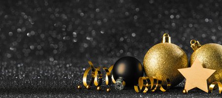 gold and black christmas balls on black bokeh background