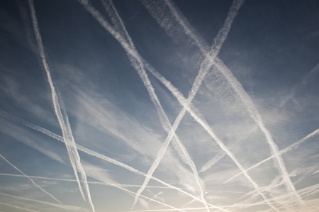 Pattern of airplane trails of condensed air crisscrossing each other against the blue skyの写真素材
