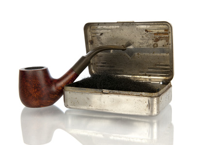 Vintage brown pipe with filled iron tobacco box in closeup and isolated in whiteの写真素材