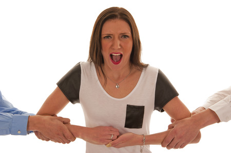 Two boys pulling the arms of a screaming and resisting girlの写真素材