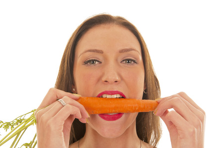 Young girl puts her teeth in an orange carrotの写真素材
