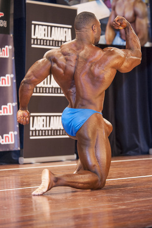 SCHIEDAM, THE NETHERLANDS - APRIL 26, 2015. Male bodybuilder Michael Muzo shows his big biceps and muscular back at the 38th Dutch National Championship Bodybuilding and Fitness of the IFBB Netherlands (NBBF) on april 26, 2015 in Theatre "aan de Schie" atのeditorial素材