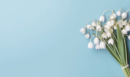 A snowdrop flowers bouquet on a pastel blue background with empty copyspace. mother's day concept. top view. Created with generative AI toolsの素材