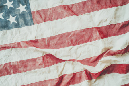 Close up of a vintage American flag with creased fabric showing stars and stripes in vibrant colors.の素材