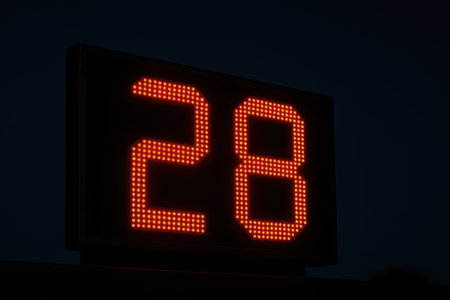 Bright red led digital scoreboard displaying the number twenty eight against a dark nighttime background.の素材