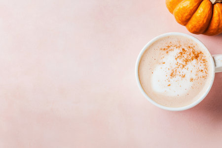 Warm pumpkin spice latte on pink table with autumn pumpkin garnish.の素材