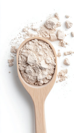 Wooden spoon filled with powdered clay on white surface for skincare and cosmetics.の素材