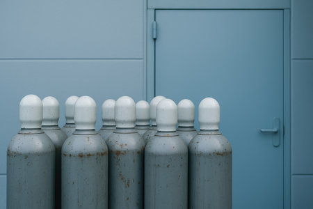 industrial gas cylinders arranged in front of a closed metal door in a minimalistic blue toned facility environment.の素材