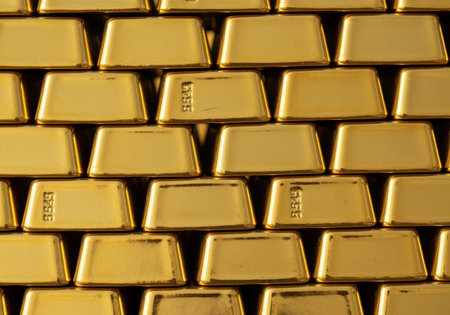 Stacked gold bars with shiny metallic surfaces arranged in rows, symbolizing wealth, prosperity, and financial investment.の素材