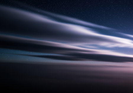 Long streaks of clouds illuminated by twilight under a starlit sky with soft gradient colors and tranquil nighttime atmosphere.の素材
