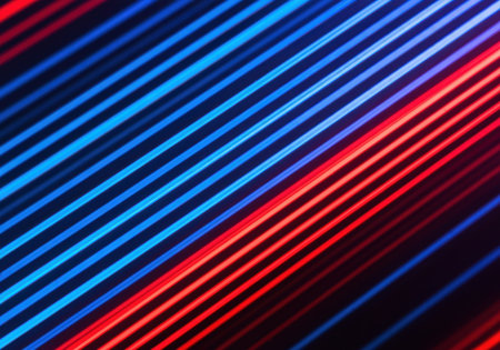 Dynamic abstract pattern of intersecting neon red and blue light streaks glowing against a dark background with modern futuristic energy.の素材