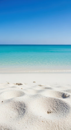 White sandy beach under clear blue sky and turquoise sea with gentle waves on a bright summer day.の素材