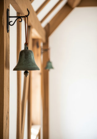 Antique bronze bell hanging on wooden frame indoors in bright natural light with minimalistic scandinavian interior design.の素材